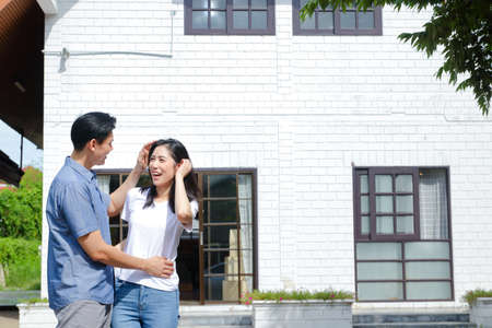Asian male and female couples stand, hug, and smile happily in front of the new house. The concept of starting a married life In order to create a happy family. copy spaceの写真素材