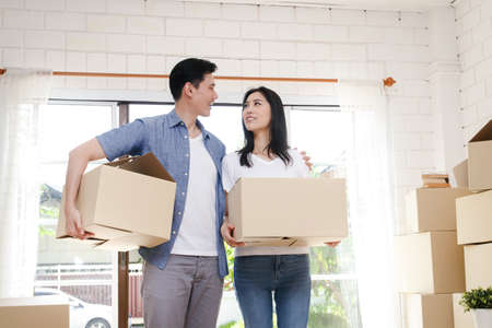 Asian couple buy a new house, hold a paper box to put things in. Move into a new house. Concept of...