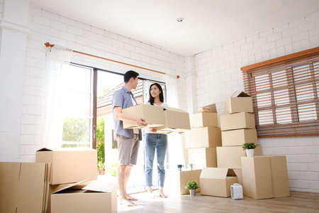 Asian couple buy a new house, hold a paper box to put things in. Move into a new house. Concept of starting a new life, creating a family. copy spaceの写真素材