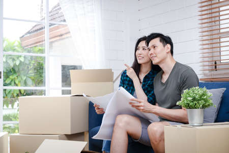 Asian men and women couples Hold the blueprint, the new house is happy to build a family together....