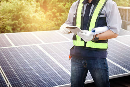 A male engineer holds a tablet to inspect the solar cell system. Concept of the electric power...