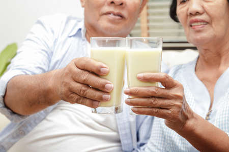 An elderly Asian couple drinks calcium-rich milk to prevent osteoporosis. Make the body strong and healthyの写真素材
