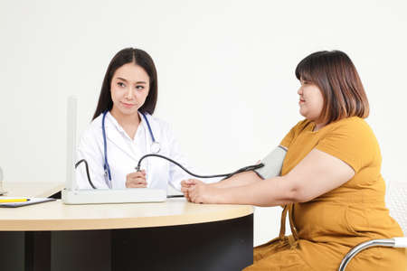 Asian female doctors measure pressure on very obese patients for health checks and disease detection for treatment.の写真素材