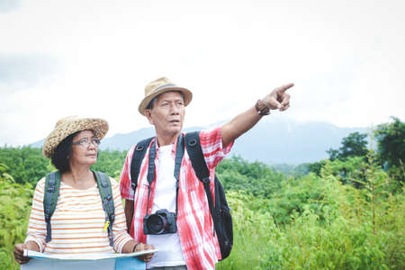 Elderly Asian couples trekking nature travel, holding a map, traveling happily in retirement. The concept of elderly people.の写真素材
