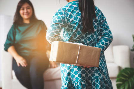 A small daughter held a gift in a paper wrap for Mom on a special day. new Year festival. Christmas season. Happy birthdayの写真素材