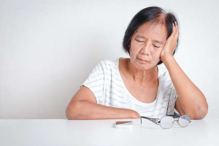 Asian elderly woman have stress Feeling very worried about problems with retirement life. White...