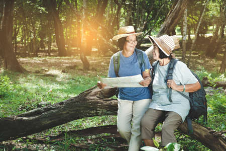Two elderly women hiking Carrying a backpack and carrying a map. The concept of senior citizens traveling natureの写真素材