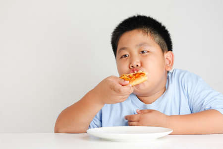 Fat kids eat pizza happily. If eaten in large amounts, the body fat is not healthy.の写真素材