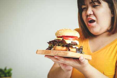 Fat Asian woman eating a hamburger. Full of things that cause diabetes, heart disease, obesity and...
