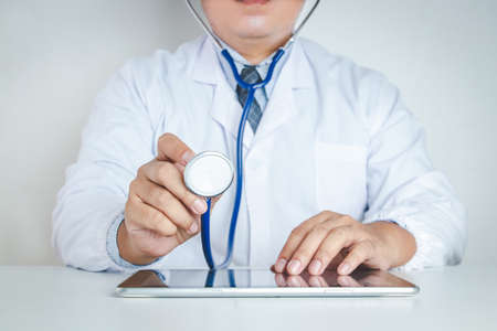 The doctor uses stethoscope to check the patient's health and use the tablet to see treatment...