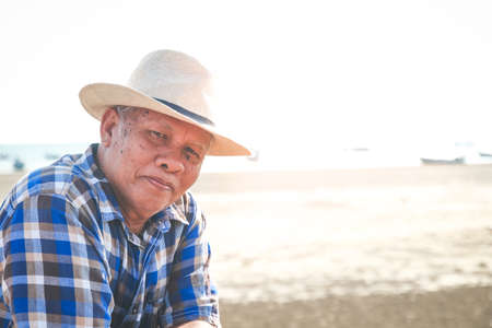 An elderly man wearing a hat to travel to the beach to relax, to live independently in retirement. Senior community conceptsの写真素材