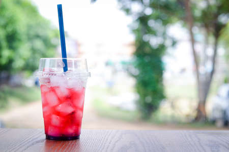 A glass of red nectar filled with ice cubes Cool down the thirst for hot weather. Placed on a wooden...