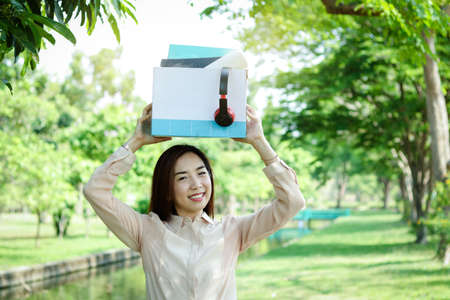 Office girl holding a white paper box, put files and music headphones Happy smileの写真素材