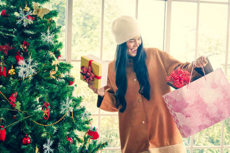 An Asian woman is happy to receive a Christmas present. The festival celebrates the birth of Jesus, which falls on the 25th of December every year.の写真素材