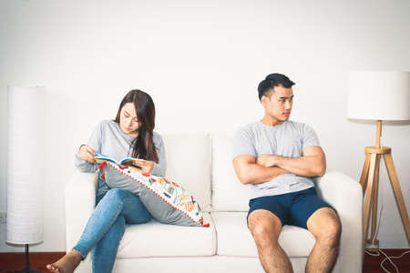 Couples just married, quarrel, refusing to talk to each other. Both were sitting on the sofa inside...