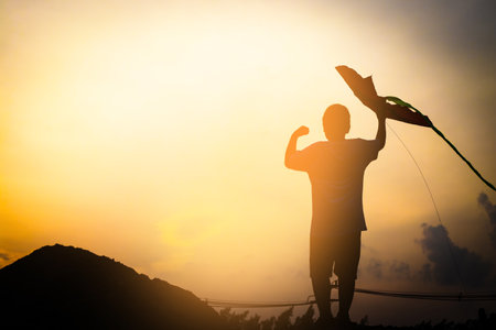 Asian boys spread their hands and hold the toys standing on high ground. silhouetteの写真素材