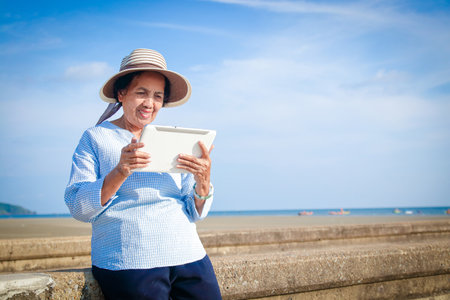 Elderly women hold intelligent tablet communication devices for video chatting, talking with their children. Happy retirement conceptの写真素材