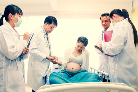 A group of doctors who take care of pregnant women closely to give birth to children safely. Hospital concept, obstetrics department and patient health careの写真素材