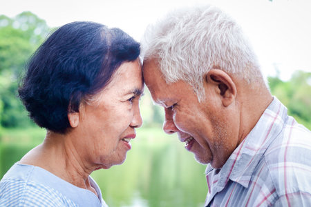 Asian couples who have lived together for over 50 years, put their foreheads close together, smiling...