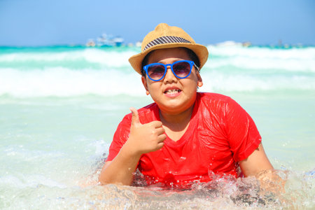 Boys wearing hats and sunglasses playing in the seaの写真素材