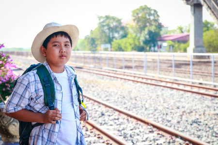 Asian little boy carrying a blue backpack Standing waiting for the train to go to schoolの写真素材