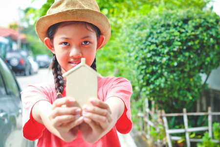 Asian children hold a wooden piggy bank, a small house.の写真素材