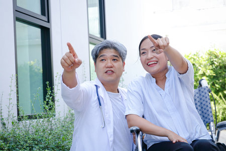 Male doctors and female patients sitting on a wheelchair Both pointed their fingers forward.の写真素材