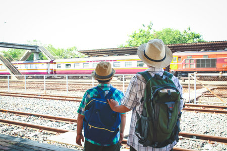 Two children carrying a backpack Watching the train runningの写真素材