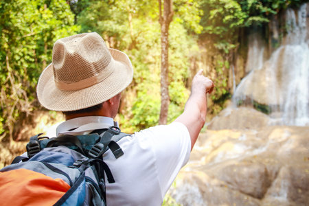 A young man carrying an orange backpack Holding a map paper for travelingの写真素材
