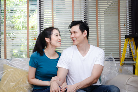 Asian male and female couples renovate their homes to be beautiful. They rested on the sofa in the living room. The concept of housing, building a familyの写真素材