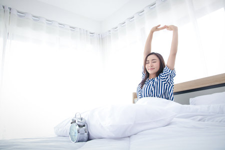 Happy asian woman Sitting on the bed in the morning bedroom. copy spaceの写真素材