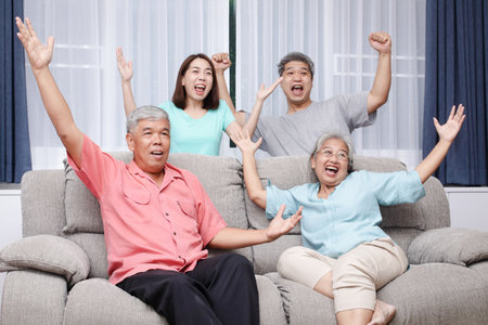 Asian family smiling happy fun cheerful In the living room at home Cheer for sports that are broadcast live on TV. Concept of living in the houseの写真素材