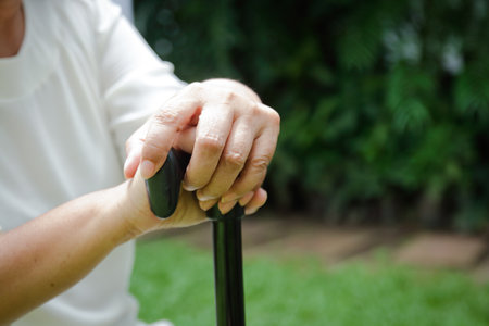 Elderly woman holding a cane to support herself Sit back and relax in the garden at home. Concept of health careの写真素材