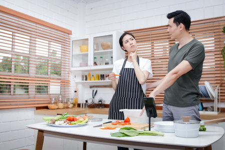 Asian couples have the joy of cooking in the kitchen at home. Watch video tutorials made online via smartphone. Food concept. copy spaceの写真素材