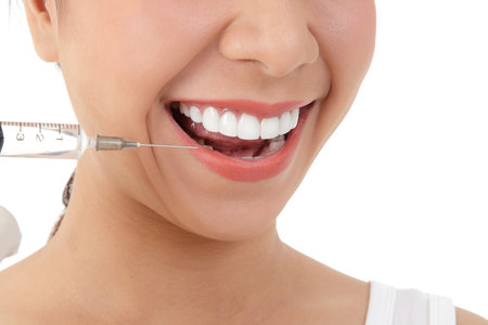 The doctor hand held the syringe to inject the girl's face to treat acne. Skin care beauty concept . White backgroundの写真素材