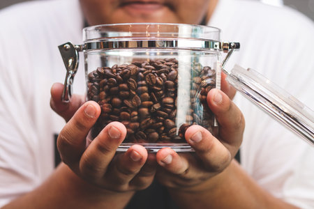 Fat man holding a jar of roasted coffee beans He happily inhaled the fragrance. Concept Barista Cafeの写真素材