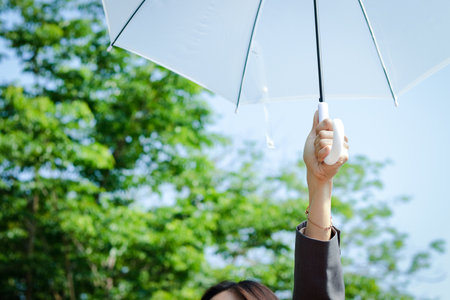 A business woman wearing a suit, she holds a shaded white umbrella.の写真素材