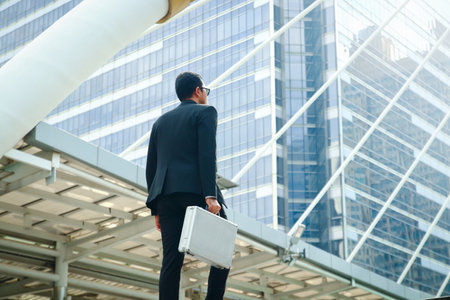 Asian businessmen wearing suits. Hold the bag up the stairs.の写真素材