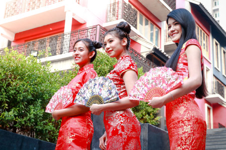 Beautiful woman group wearing three Chinese dress Standing holding a Chinese fan facing the same way Smile for the new yearの写真素材