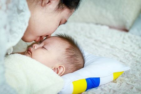 Mom's love She hugs the baby in the arms, sitting in the bed in the bedroom.の写真素材