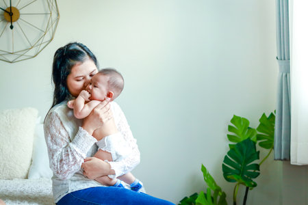 Mom's love She hugs the baby in the arms, sitting in the bed in the bedroom.の写真素材