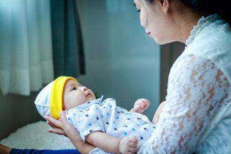 Mother holding baby baby playing in the bedroom