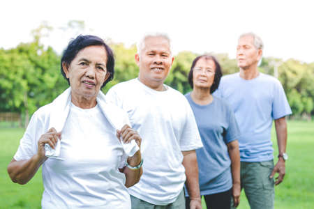 Four elderly Asian people exercise in the park.