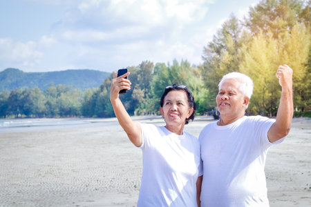 Happy, elderly couples come to the sea to relax Hold the phone, take pictures together, smile, have funの写真素材