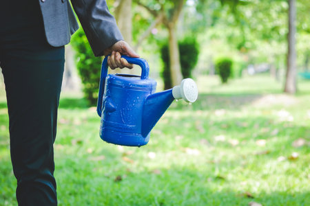 Women wearing a work suit holding a watering can in the gardenの写真素材