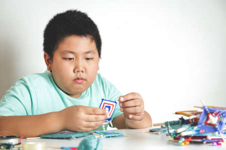 Asian boys sit to make toys with their own hands. White backgroundの写真素材