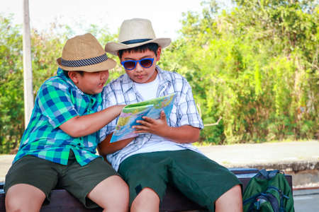 Two children watching the map Sit and wait for the train at the station to travelの写真素材