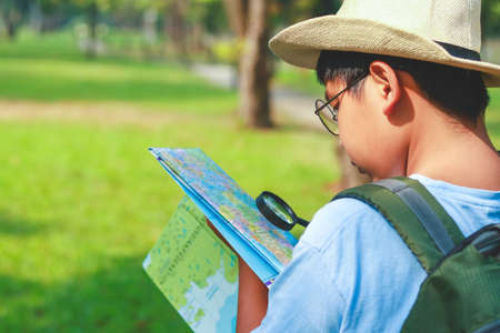 Asian male students Carrying a travel backpack, wearing a hat, holding a map to travel to learn