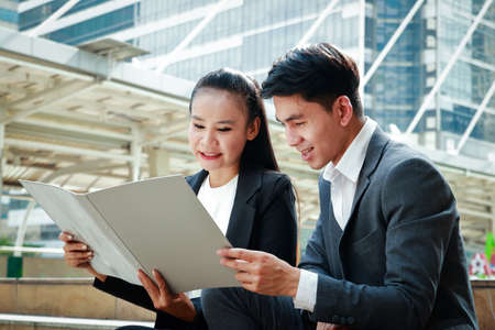 Male and female office workers sit outdoors and talk about planning.の写真素材
