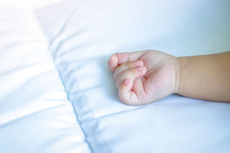 Baby hands on a white mattress have space.の写真素材